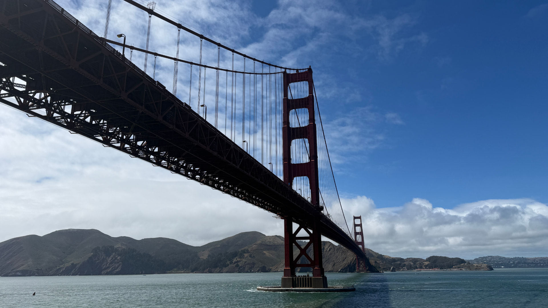 The Golden Gate Bridge seen from below against a blue sky over San Francisco Bay